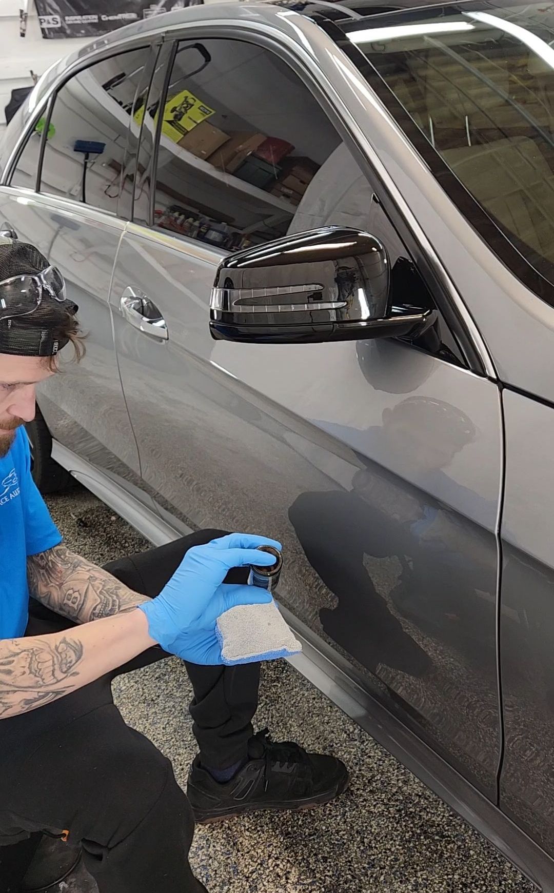 A man is cleaning the side of a car with a sponge.