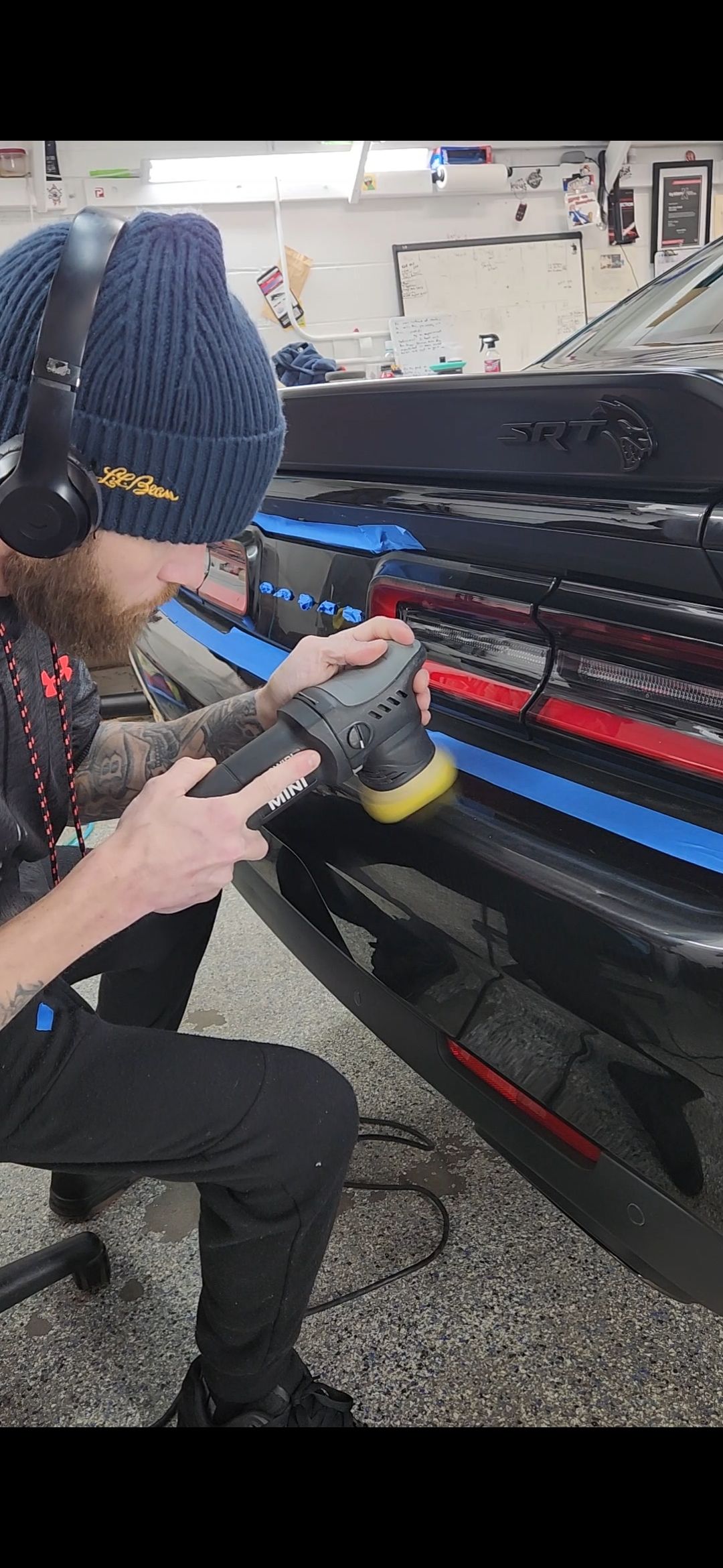 A man is polishing the front bumper of a truck.