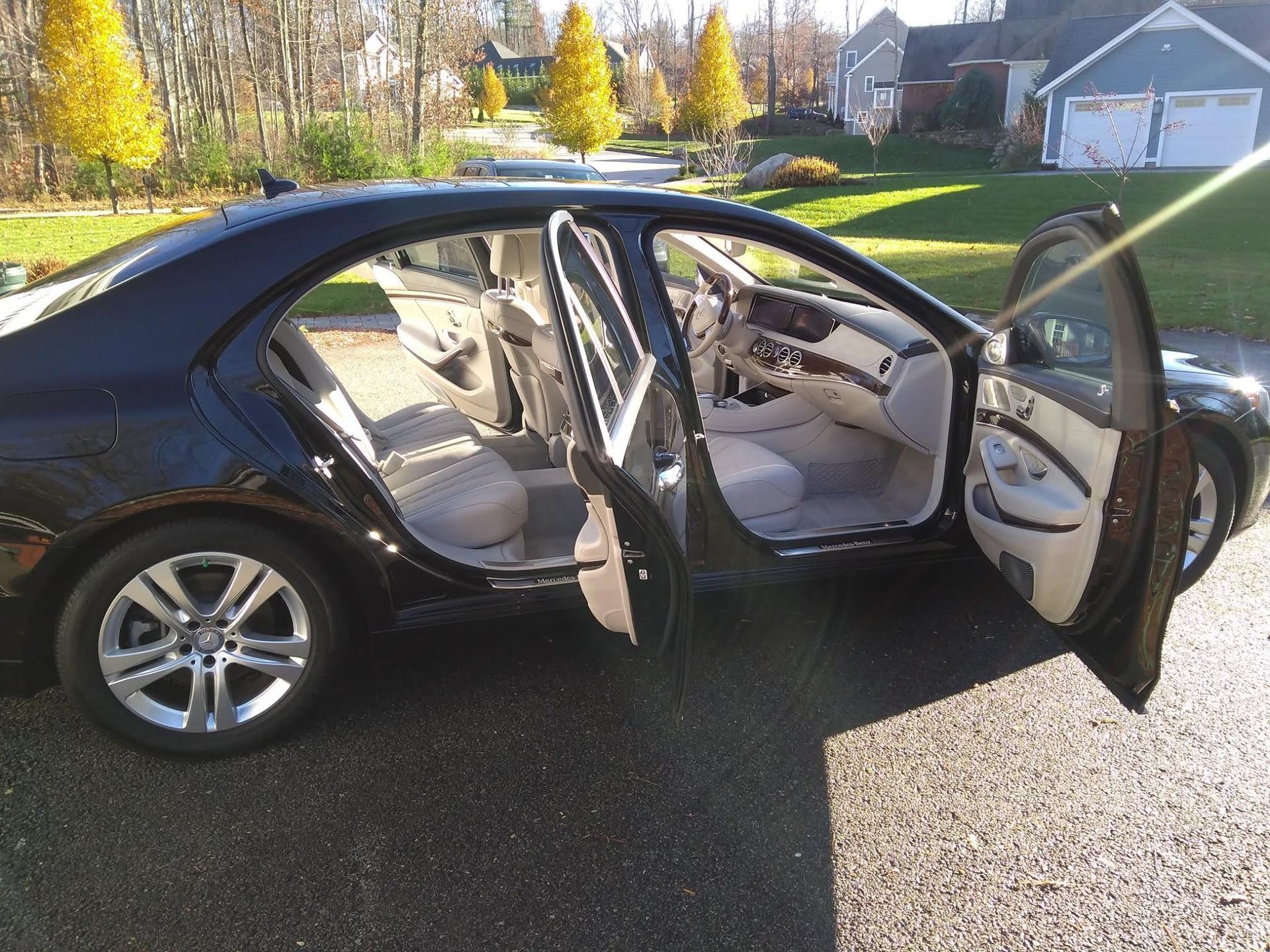 A black car is parked in a driveway with its doors open