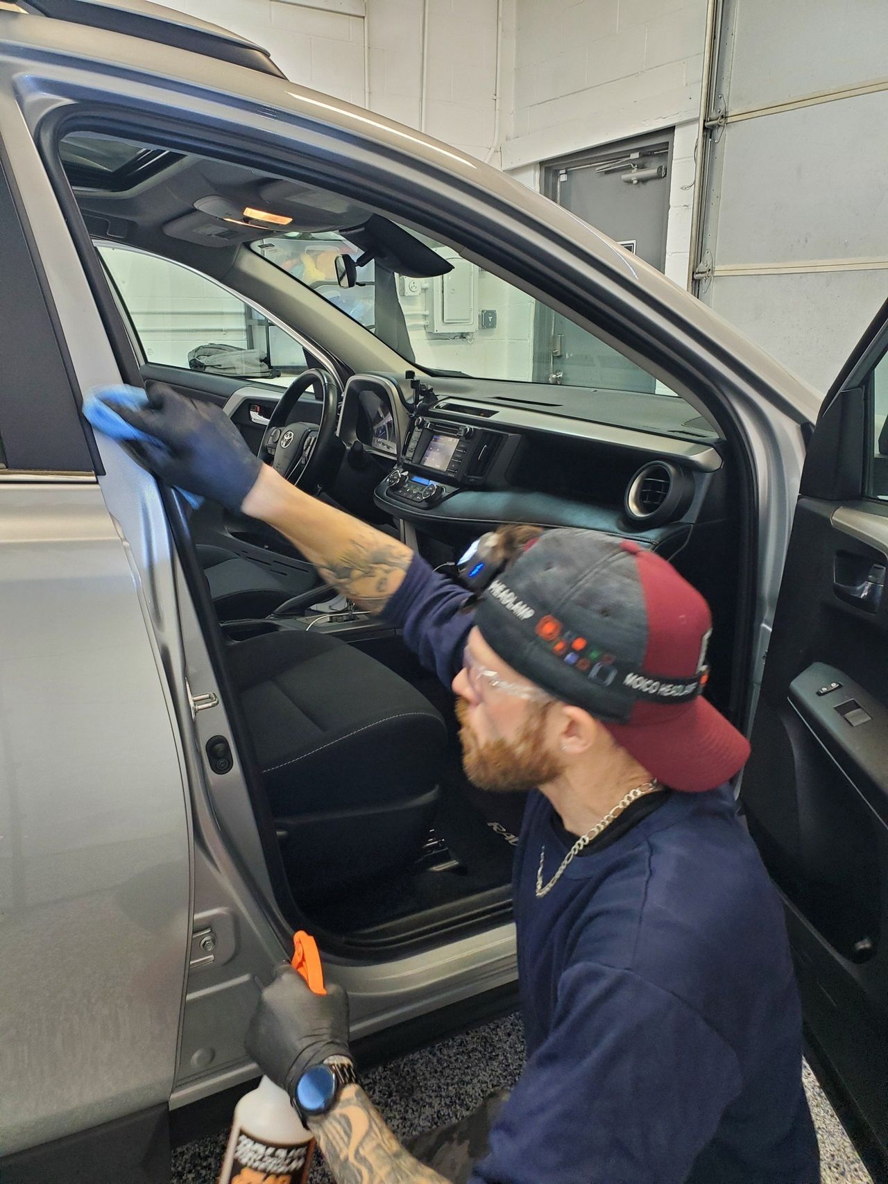 A man is cleaning the inside of a car with a cloth.