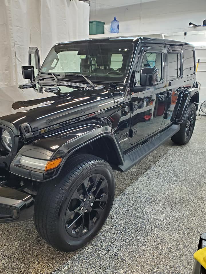 A black jeep is parked in a garage.