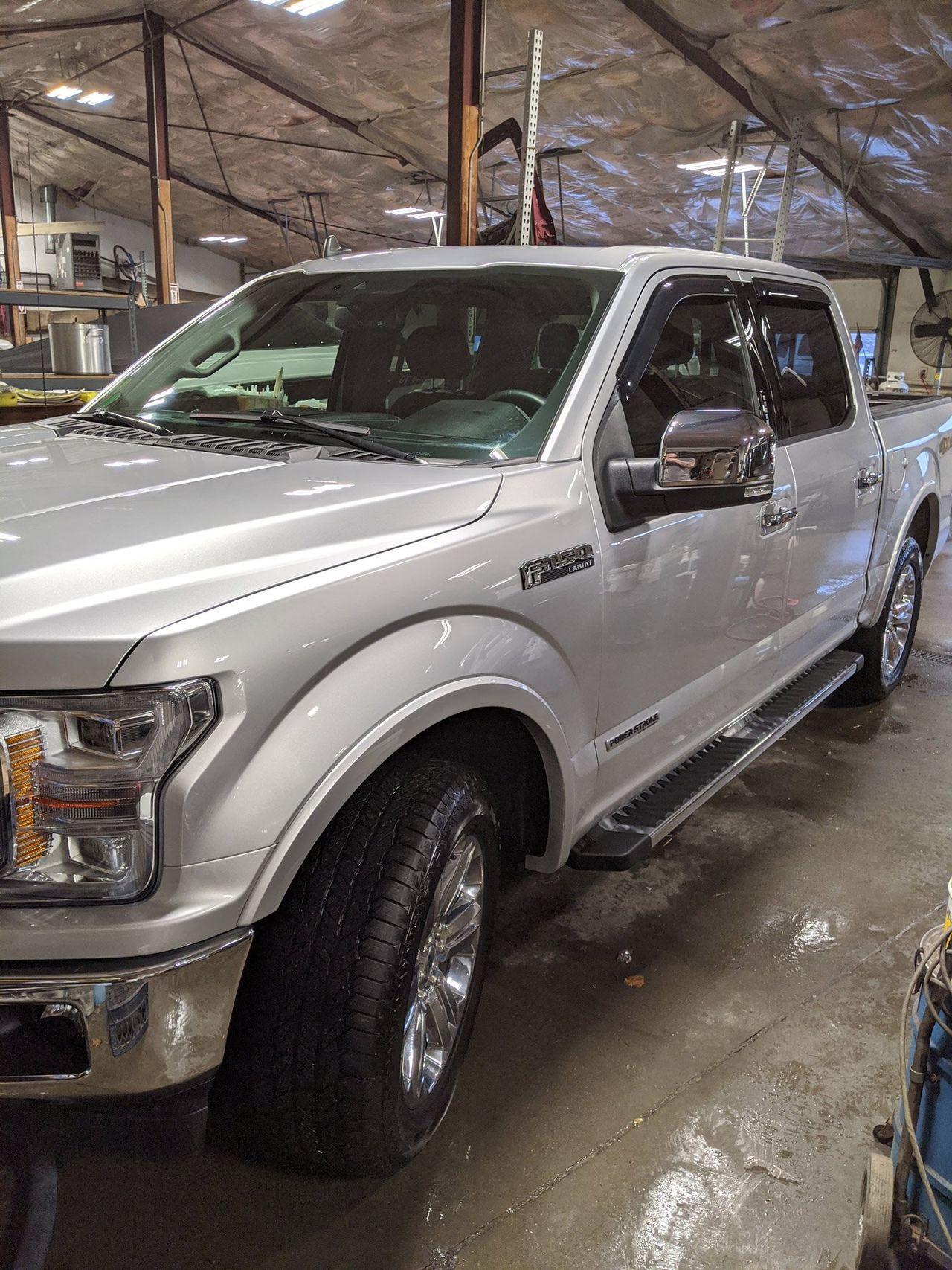 A silver pickup truck is parked in a garage.