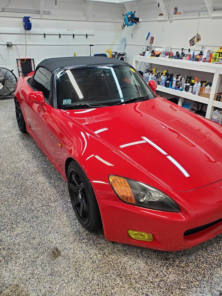 A red sports car is parked in a garage.
