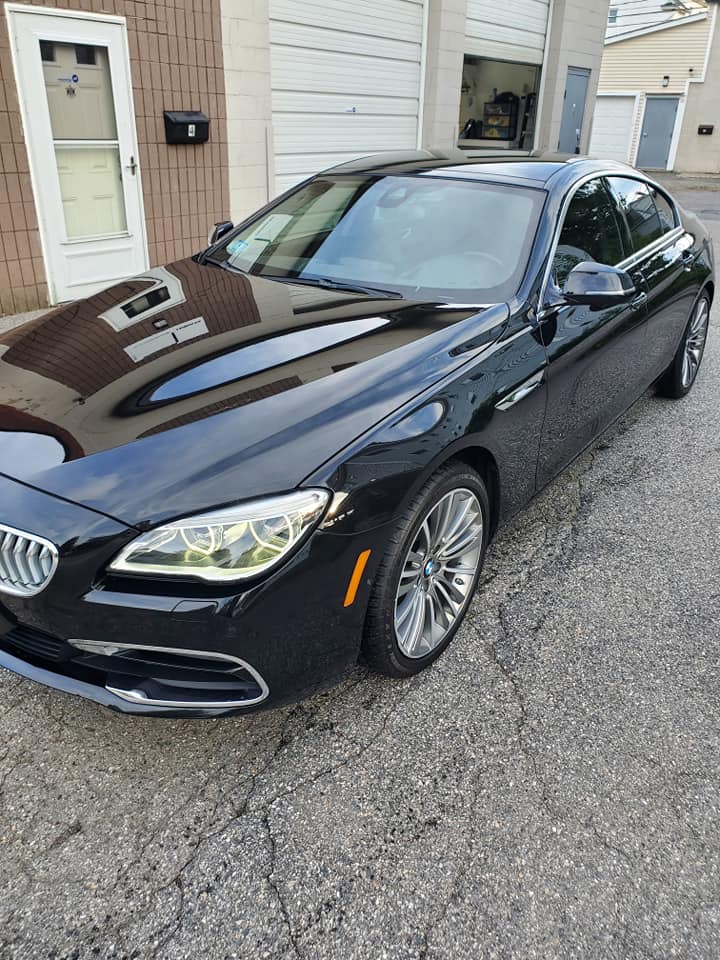 A black bmw 6 series is parked in front of a garage.