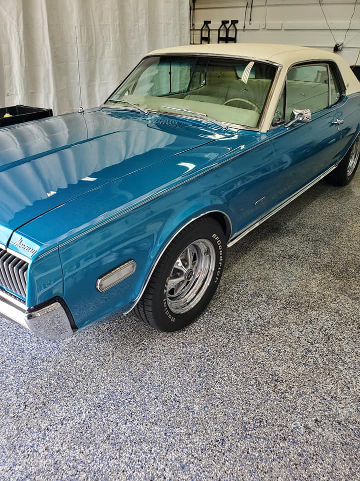 A blue and white car is parked in a garage.