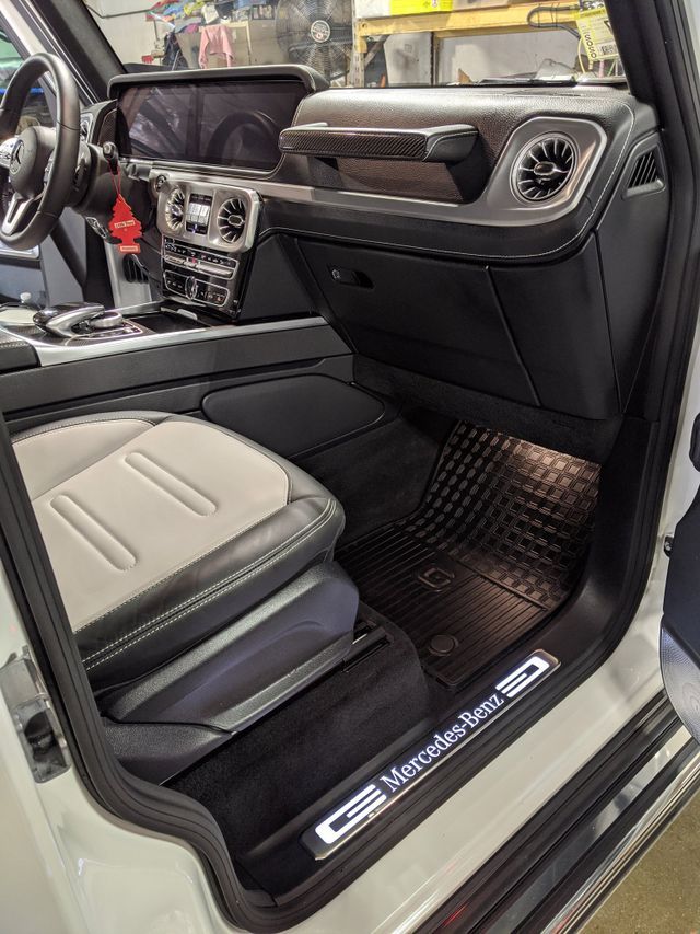 The interior of a white mercedes benz g63 with the door open.