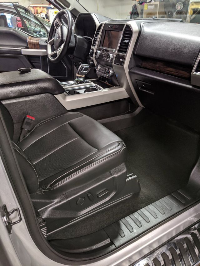 The interior of a silver ford f150 truck with the door open.