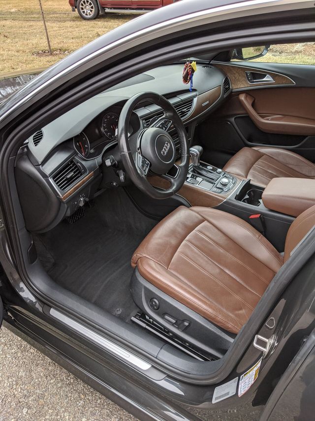 The interior of a black car with brown seats and a steering wheel.