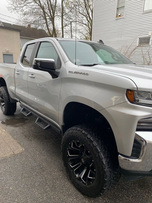 A silver pickup truck is parked in front of a house.