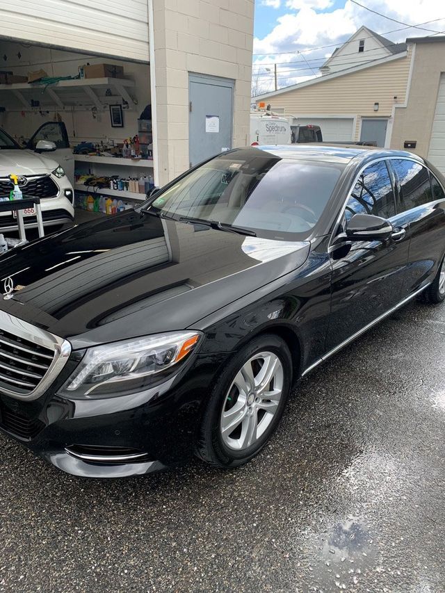 A black mercedes benz s class is parked in front of a garage.