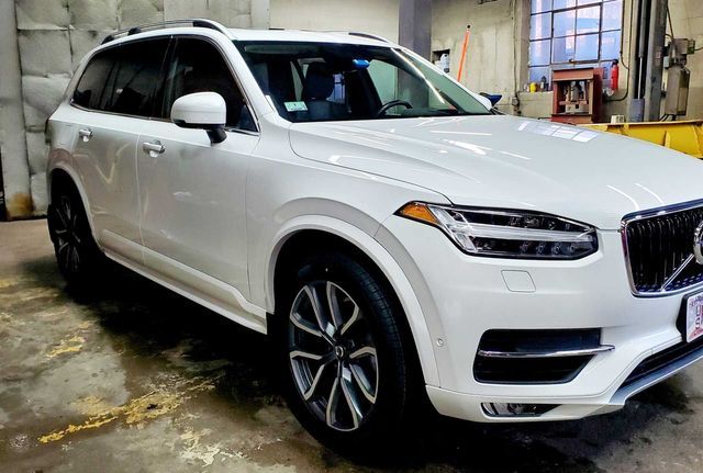A white volvo xc90 is parked in a garage.