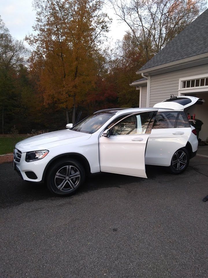 A white suv is parked in a driveway with its doors open.