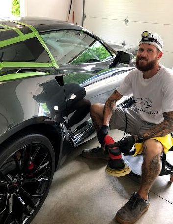A man is polishing a car in a garage.
