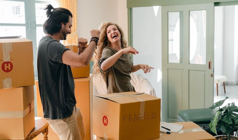 A man and woman laughing with moving boxes