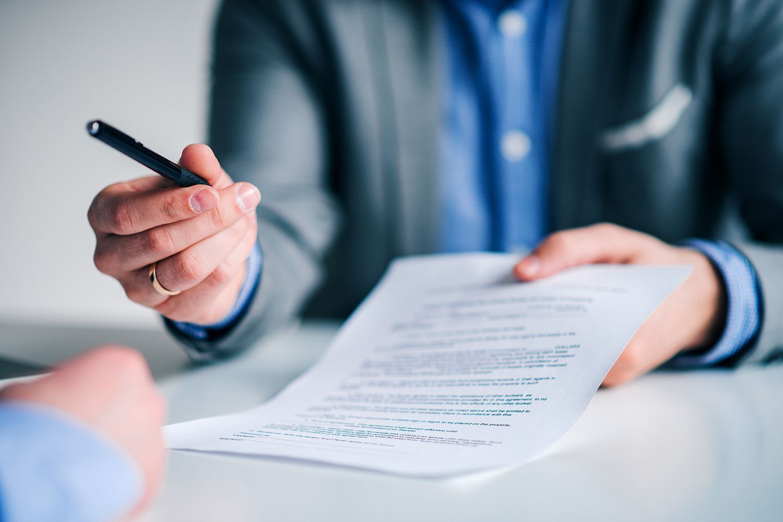 Persona de traje sosteniendo un documento con un bolígrafo, lista para firmar.