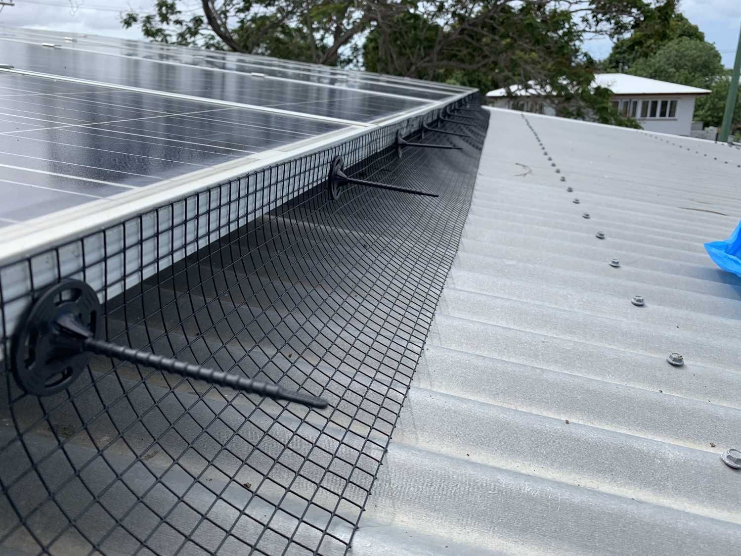 A roof with solar panels and a bird net on it.