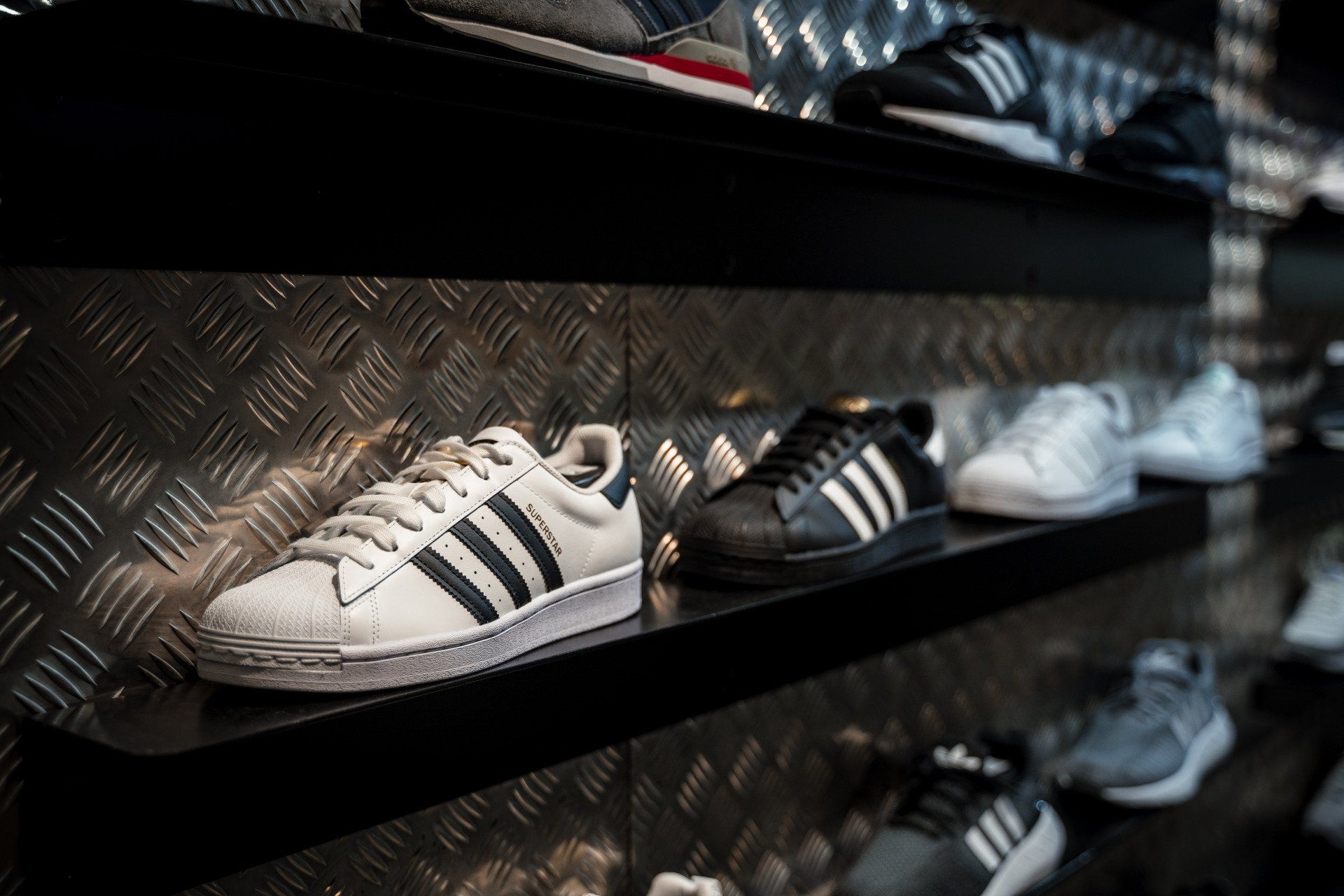 In einem Geschäft steht eine Reihe von Adidas-Schuhen auf einem Regal.