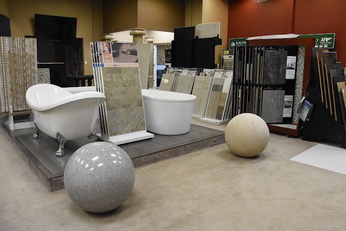 Bathroom tile and fixtures showroom. Displays include bathtubs, tile samples, and decorative spheres.