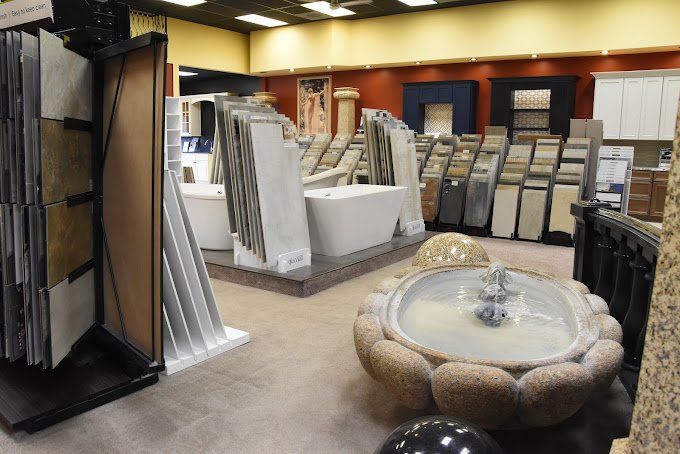 Interior of a tile and bathroom showroom with various displays of tile, sinks, and a stone fountain.