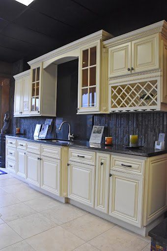 Cream-colored kitchen cabinets with black countertops and backsplash, showcasing a built-in wine rack.