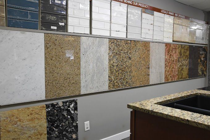 Granite and tile samples displayed on a wall in a showroom, various colors and patterns.