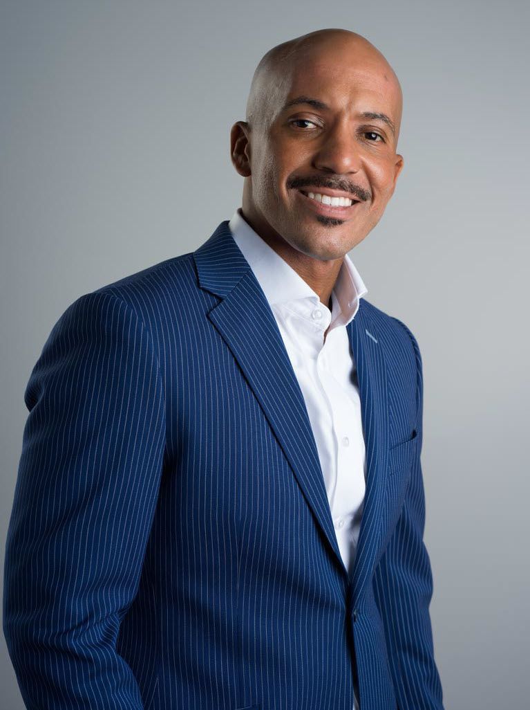 A man in a blue suit and white shirt is smiling for the camera.