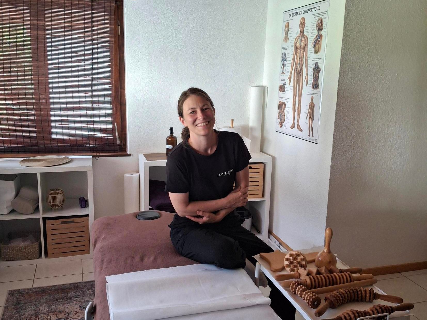 Une femme est assise sur une table de massage dans une pièce.
