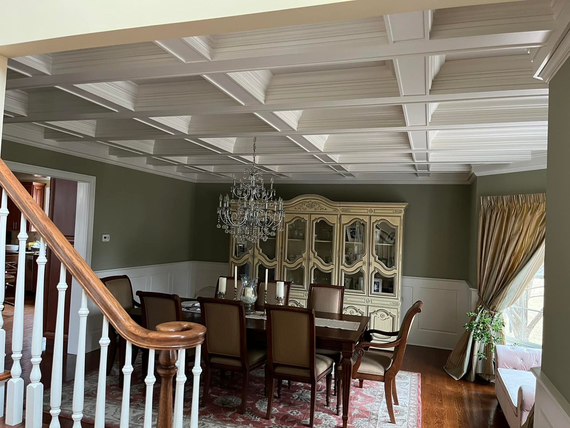 Dining room with chandelier, table, chairs, and white ceiling beams.