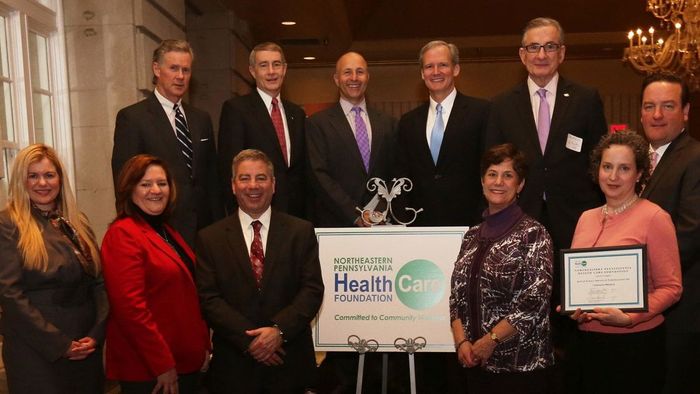 A group of people standing in front of a sign that says impact health care