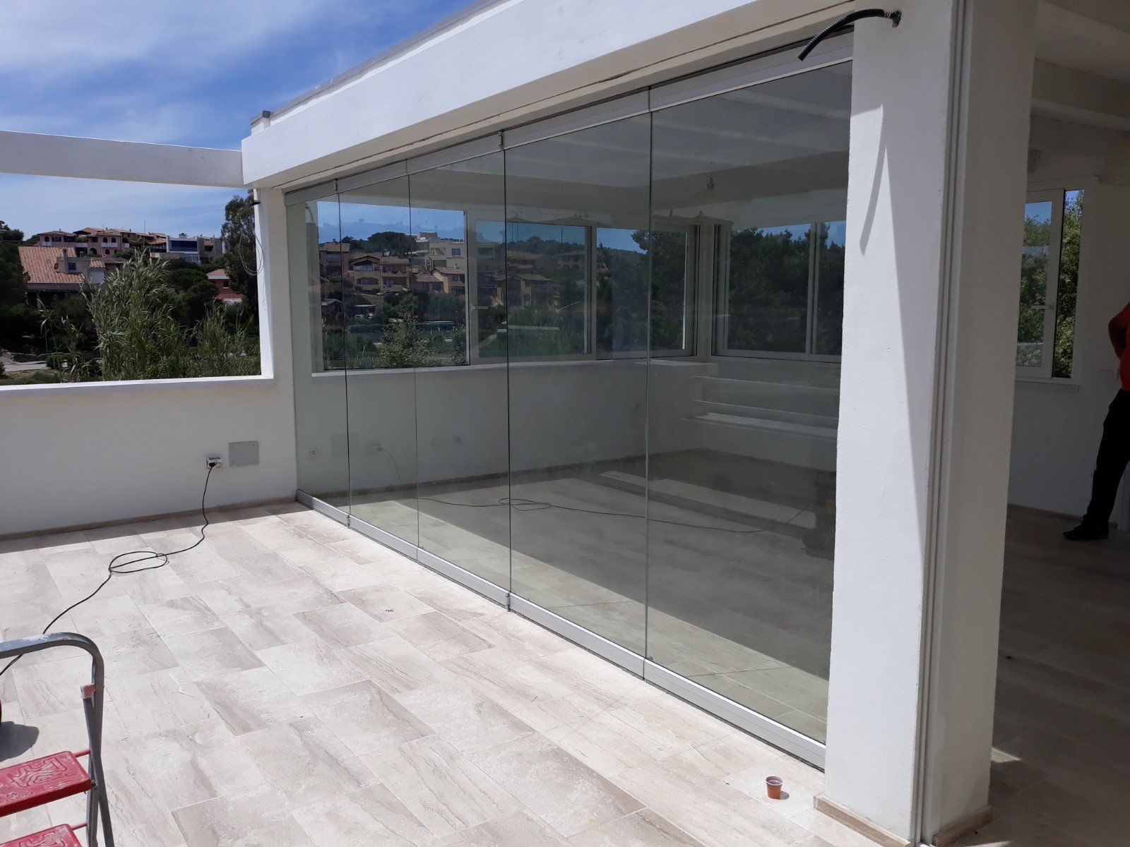 Un uomo è in piedi su un balcone con porte scorrevoli in vetro.