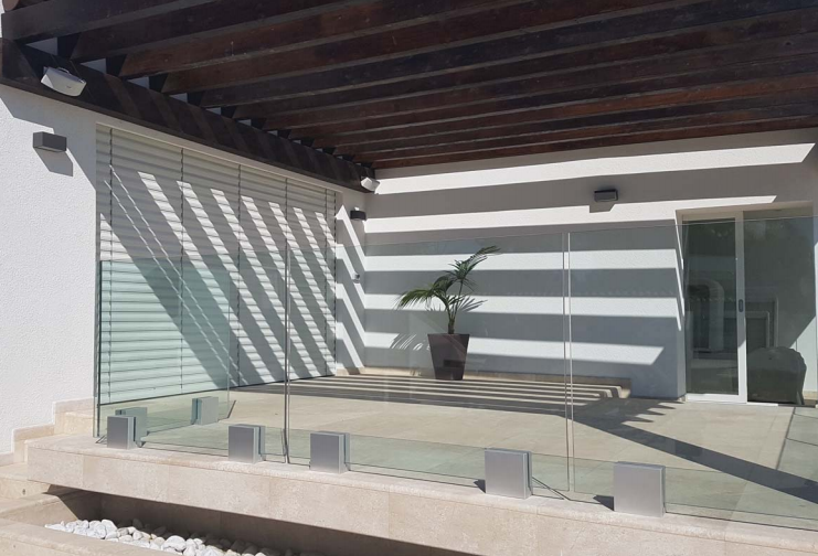 Un balcone con ringhiera in vetro e una pianta in vaso