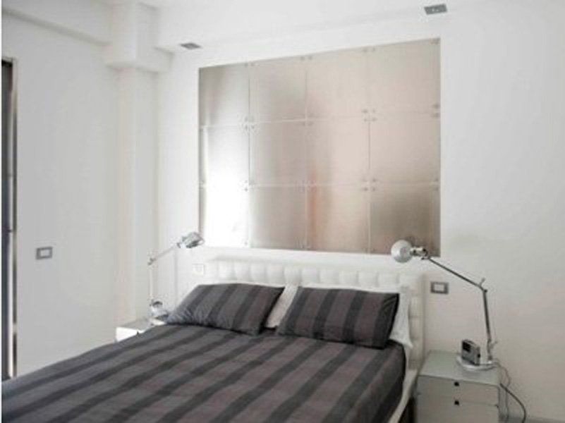 Una camera con letto a righe e testiera in acciaio inox