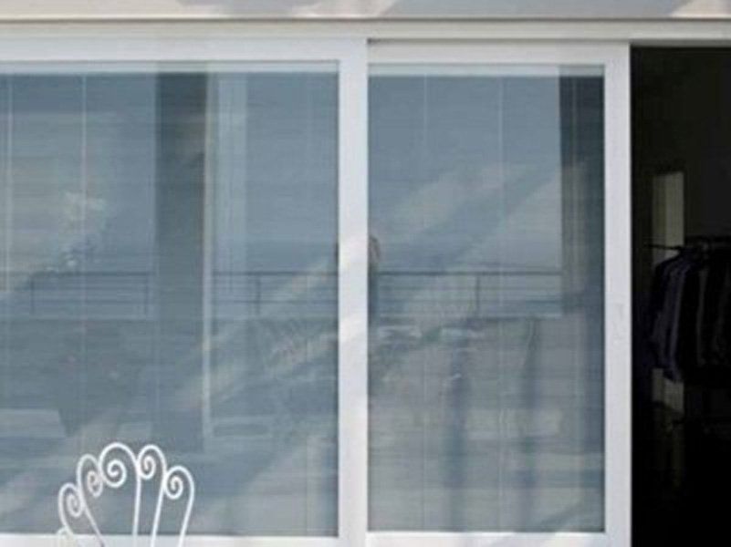 Una porta scorrevole in vetro bianco con una sedia davanti.