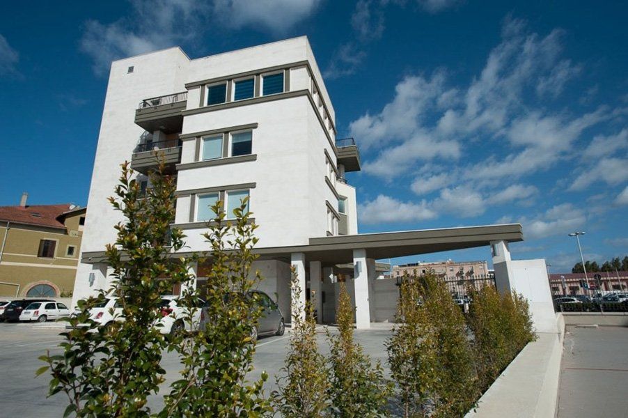 Un grande edificio bianco con delle macchine parcheggiate davanti