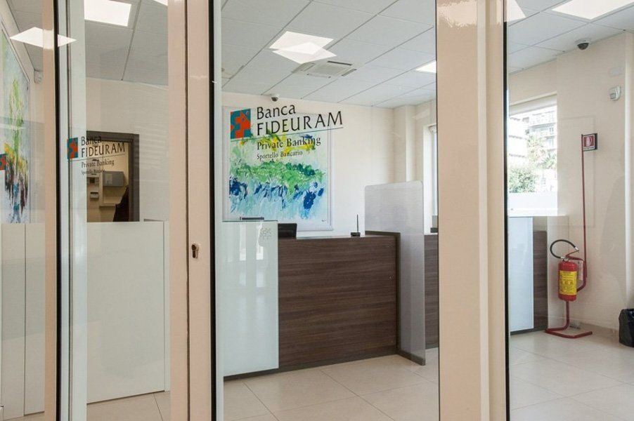 L'atrio della banca con una porta a vetri e un bancone in legno.