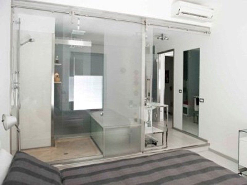 Una camera da letto con porte scorrevoli in vetro che conduce ad un bagno