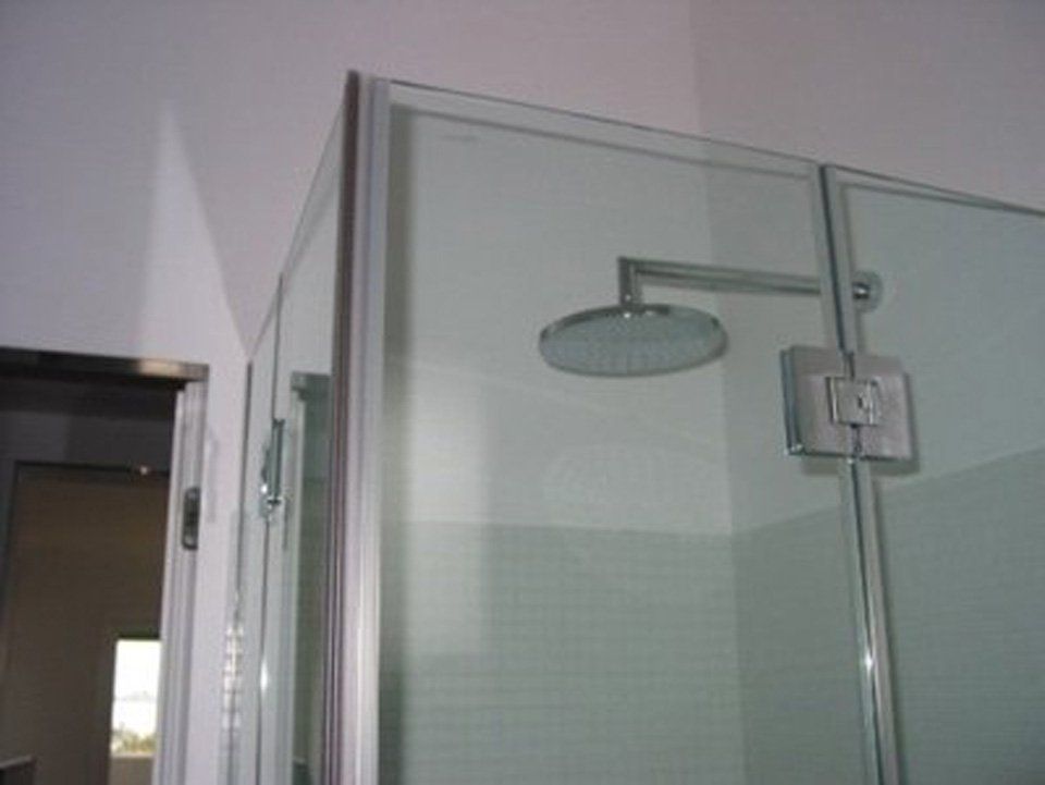 Una doccia con porta in vetro e soffione