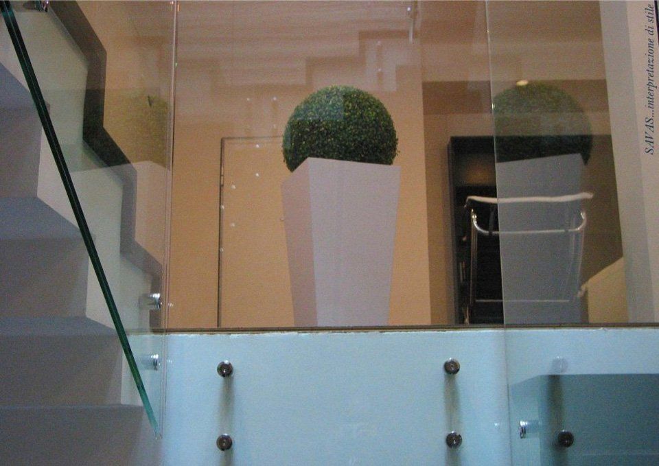 Una scala con ringhiera in vetro e una pianta in vaso