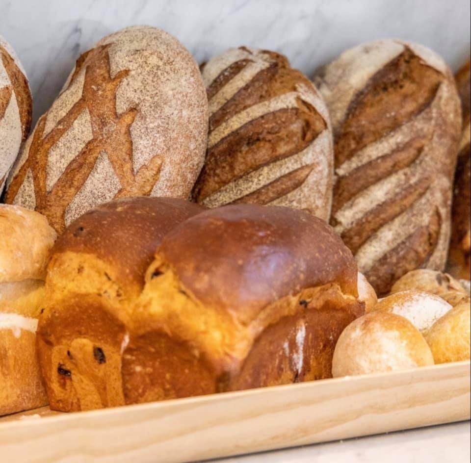 A wooden tray filled with lots of different types of bread.
