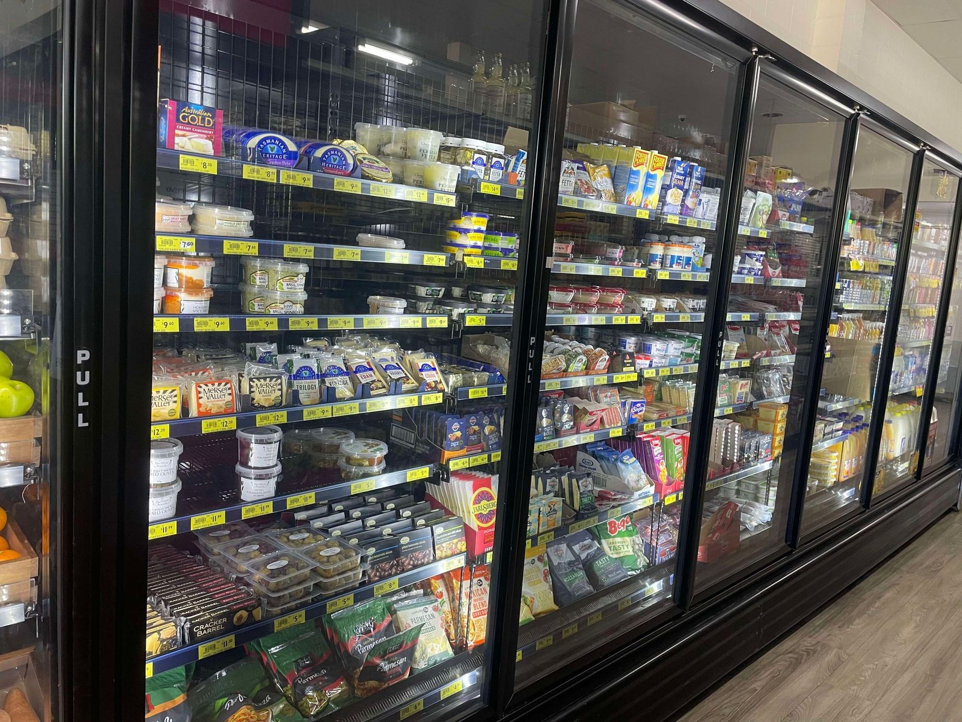 A grocery store refrigerator filled with lots of food.