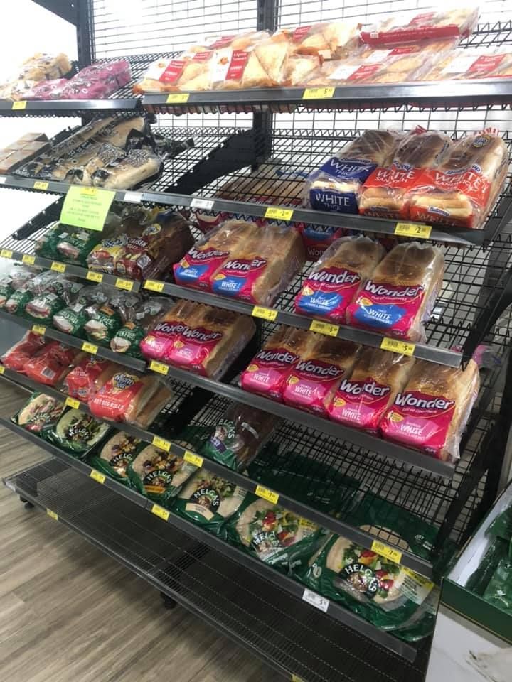 There are many different types of bread on the shelves in the bakery.