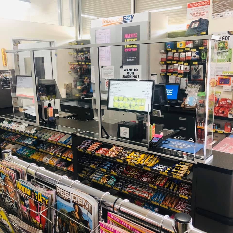 A Man In A Green Vest Is Using A Tablet Computer — Smith Street Supermarket In Darwin City, NT