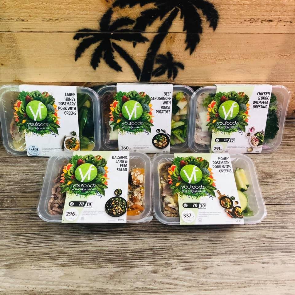 A bunch of containers of food are sitting on a wooden table