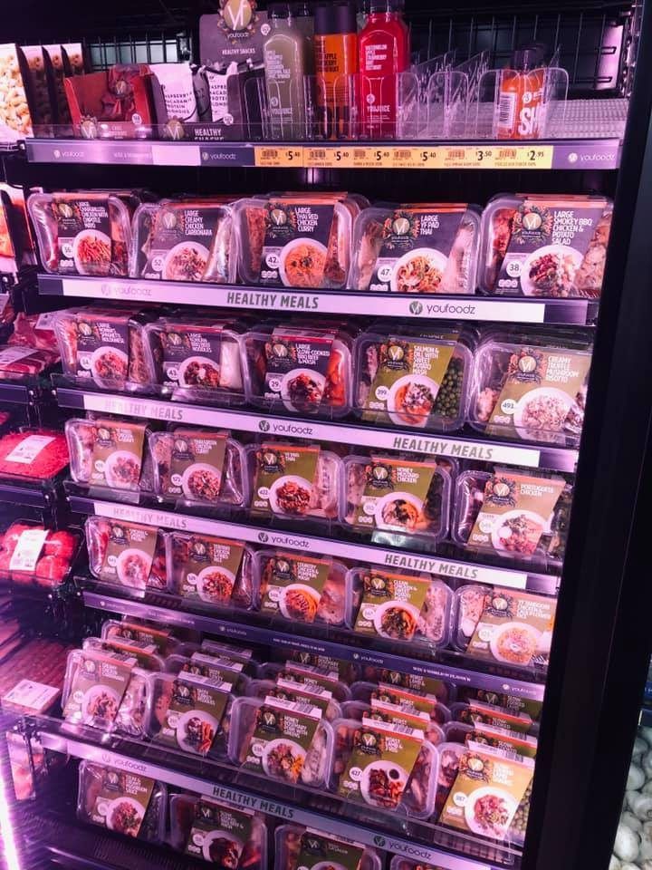 A refrigerator filled with lots of food in plastic containers. — Smith Street Supermarket In Darwin City, NT 