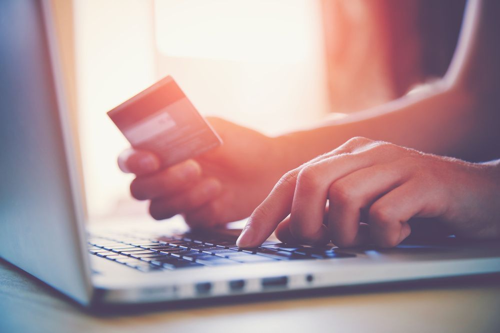 A Person Is Holding A Credit Card While Typing On A Laptop Computer — Smith Street Supermarket In Darwin City, NT 