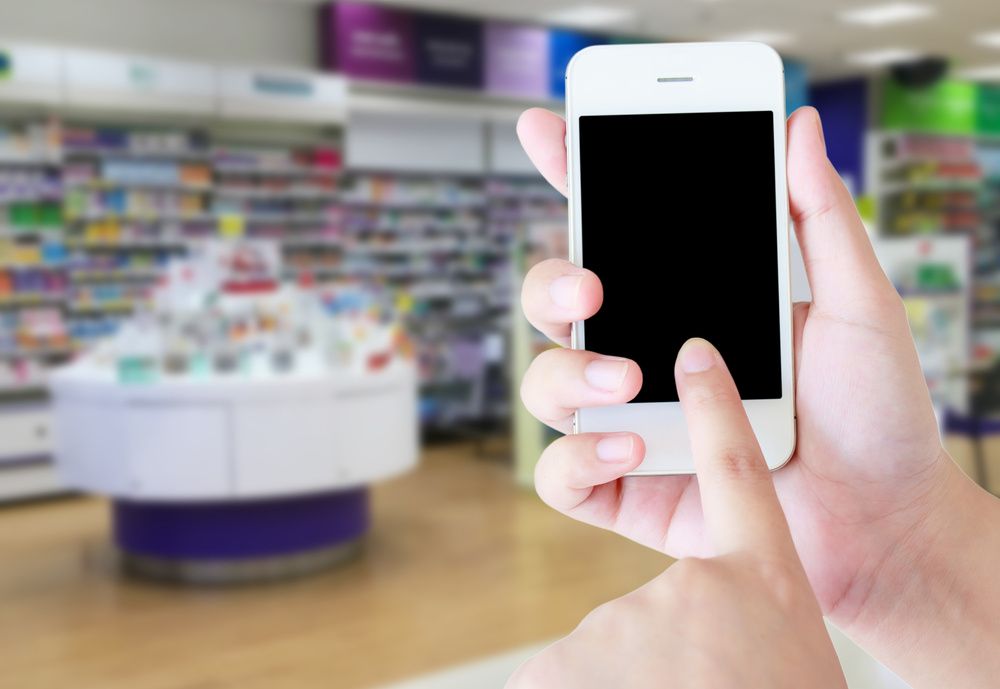 A Person Is Holding A Cell Phone In Front Of A Pharmacy — Smith Street Supermarket In Darwin City, NT 