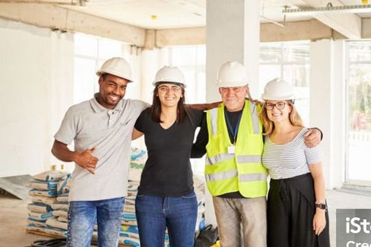 A group of construction workers are posing for a picture at a construction site.