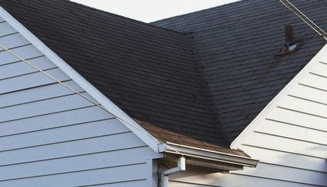 A house with a black roof and a white siding