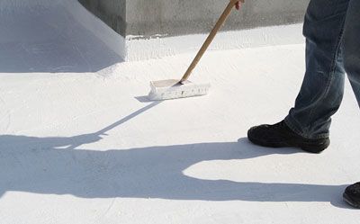 A person is coating a roof with acrylic.