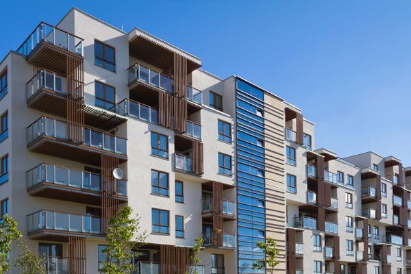 A large apartment building with balconies and a blue sky in the background.